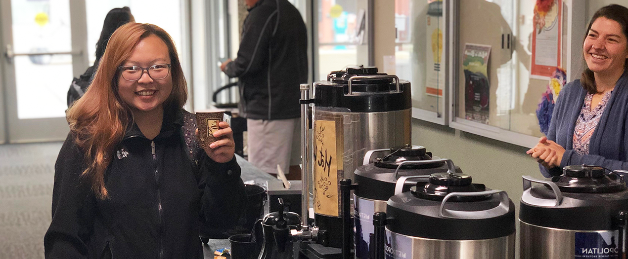 Student with coffee and scantrons at giveaway table